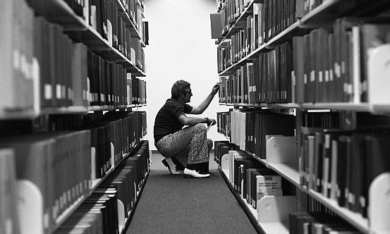 Student searching for books. Milner Library, Illinois State University, 1976.